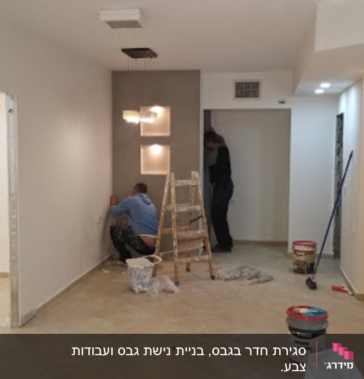 שני אנשים עובדים על קיר גבס עם סולם וכלים